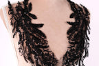 A close-up view of a mannequin torso wearing a black lace dress with intricate black sequin details.