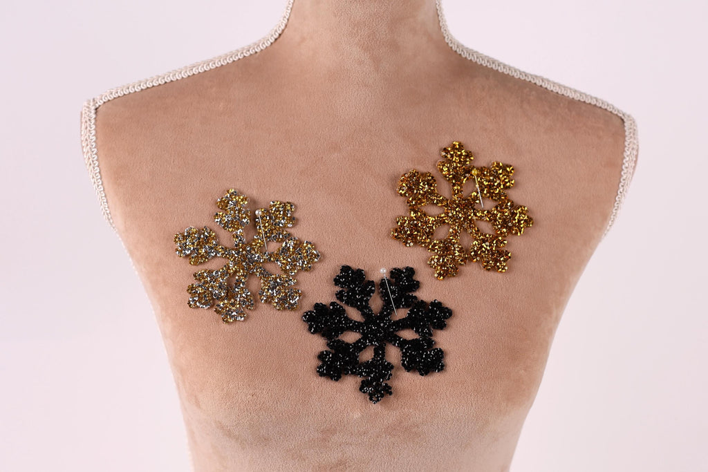 A mannequin torso with three decorative snowflake-shaped embellishments on it, each with a different color and design.