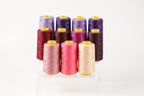 A collection of colorful spools of thread, including pink, purple, and yellow, arranged in a neat row on a white background.