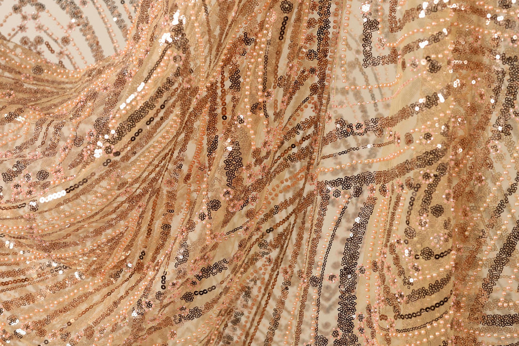 The image is a close-up of a fabric with a gold and black sequin pattern, featuring a swirling and textured appearance.