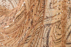 The image is a close-up of a fabric with a gold and black sequin pattern, featuring a swirling and textured appearance.