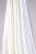 The image is a close-up of a white fabric, possibly silk or satin, with a smooth and flowing texture.