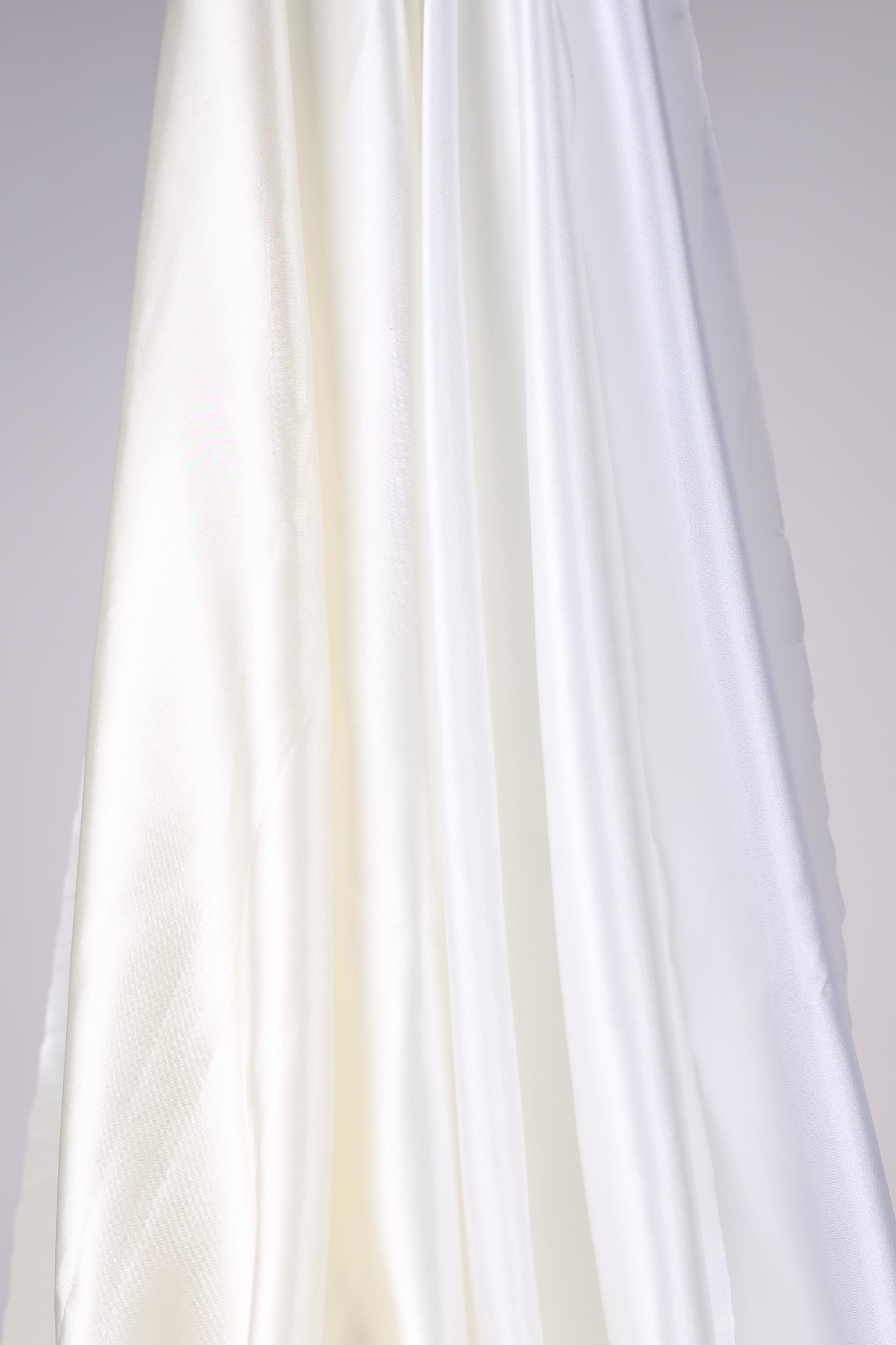 The image is a close-up of a white fabric, possibly silk or satin, with a smooth and flowing texture.