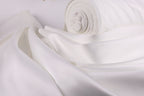 A close-up view of a white fabric, possibly silk or satin, with a rolled-up end visible.