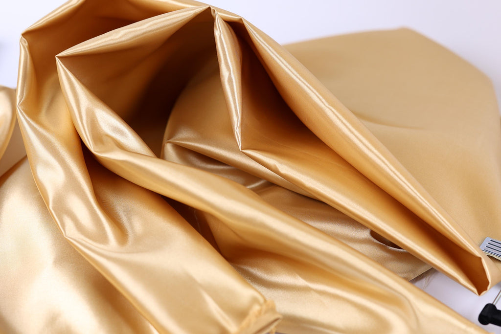 a close-up view of a shiny, golden fabric, possibly silk or satin, with a smooth and shiny texture.