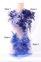 A mannequin with a dress featuring various blue floral and sequin designs, including roses and leaves, on the shoulders and chest area.