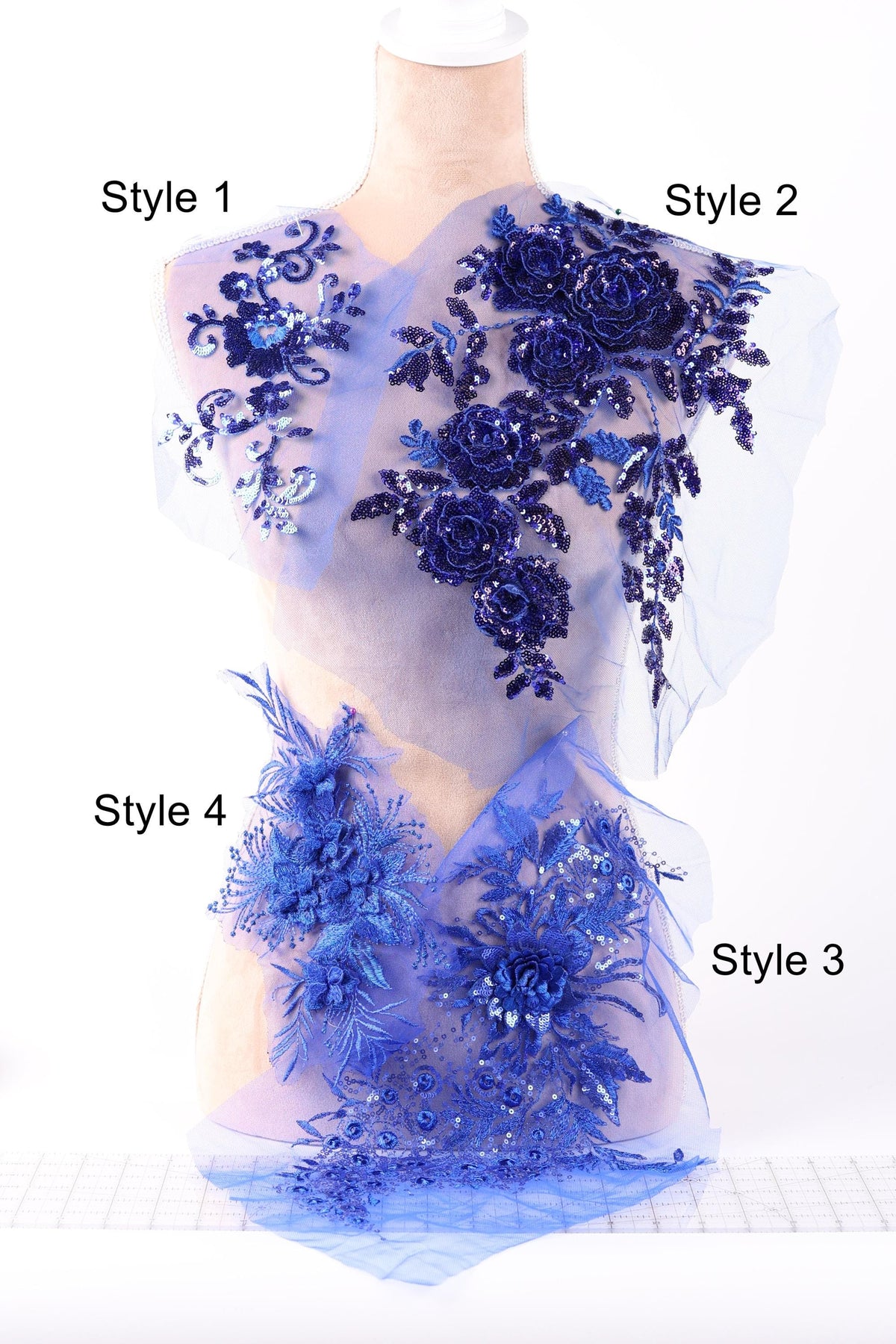 A mannequin with a dress featuring various blue floral and sequin designs, including roses and leaves, on the shoulders and chest area.