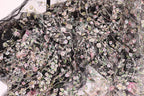The image is a close-up view of a fabric with a floral pattern, featuring a variety of colorful flowers and leaves.