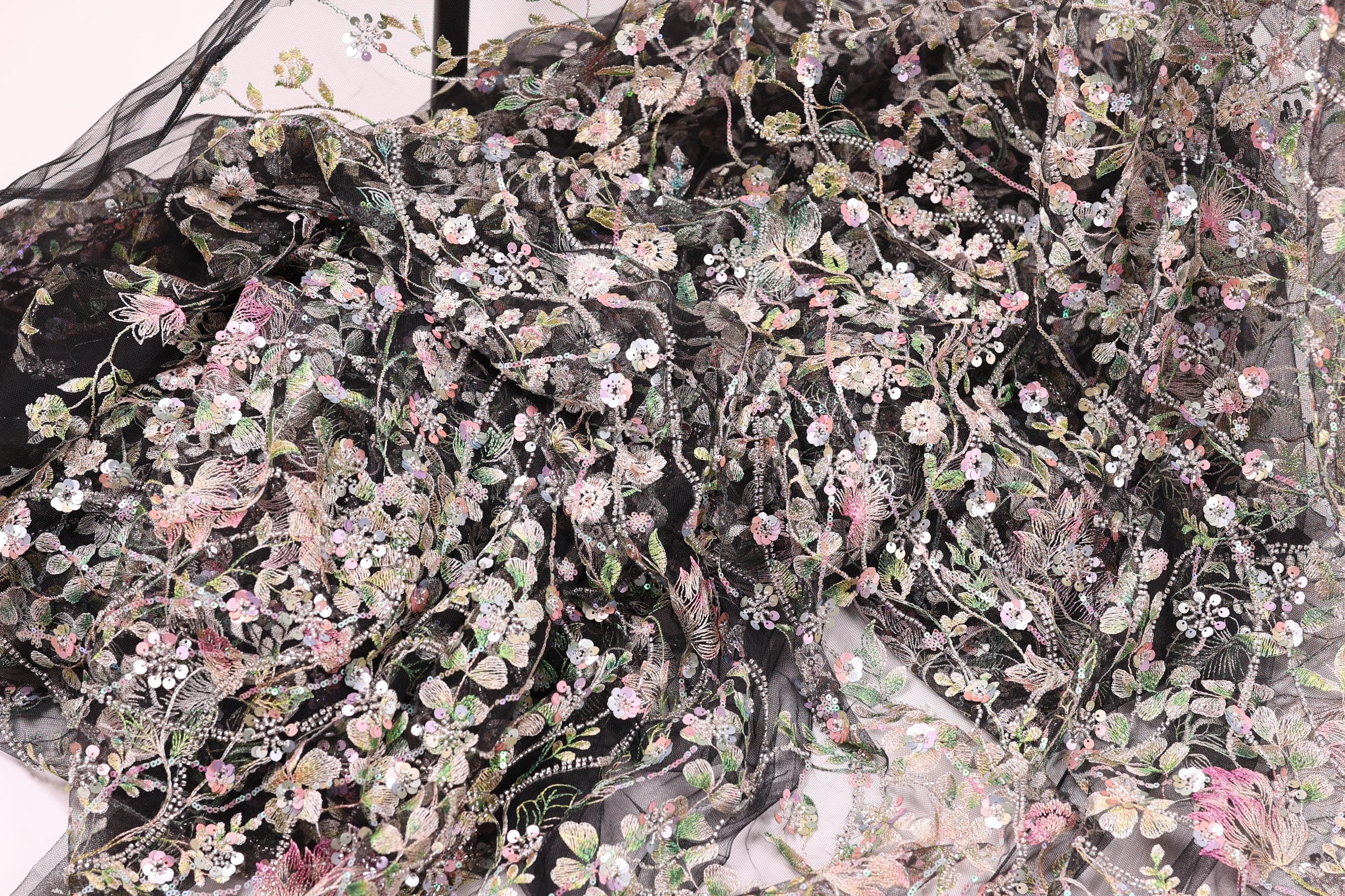 The image is a close-up view of a fabric with a floral pattern, featuring a variety of colorful flowers and leaves.