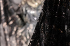a close-up view of a black sequined fabric, with a blurred background that appears to be a collage of other fabric pieces.