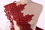 A mannequin wearing a red lace dress with intricate floral patterns.