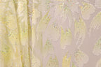 a close-up view of a fabric with a floral pattern, including yellow and white flowers with sparkling embellishments.
