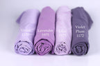 Four rolled-up fabric swatches in different shades of purple, labeled with the names of the colors: Violet, Lavender, Lilac, and Plum.