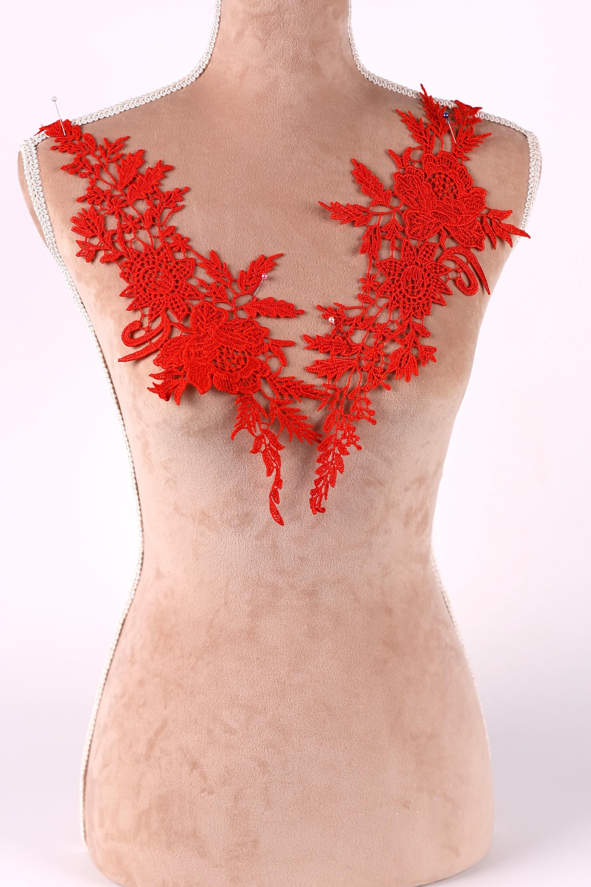 A mannequin torso wearing a red lace overlay with floral patterns.