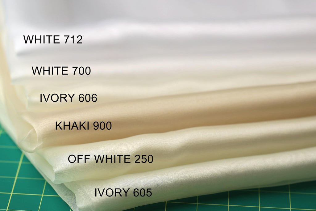 A close-up image of a stack of fabric swatches, each with a different color, arranged on a green surface.