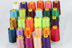 a collection of colorful spools of thread arranged in rows on a white background.