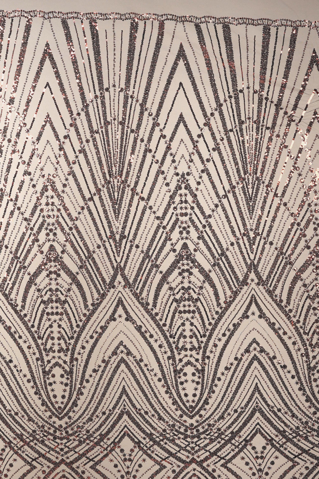 a close-up view of a sequin pattern with a repeating geometric design. The pattern consists of a series of diamond shapes and lines, creating a visually striking and intricate design. The overall appearance of the image is detailed and detailed, with the sequin pattern being the central focus.