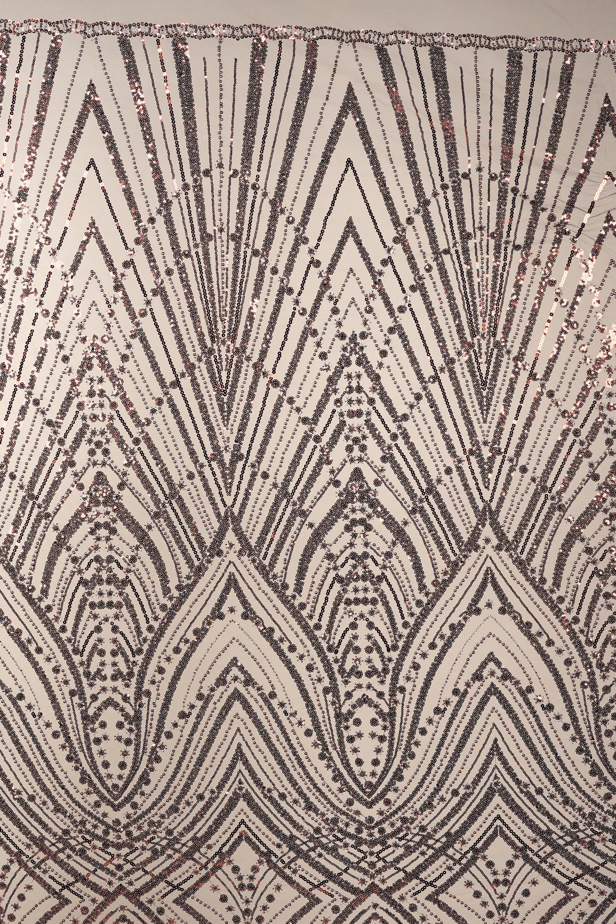 a close-up view of a sequin pattern with a repeating geometric design. The pattern consists of a series of diamond shapes and lines, creating a visually striking and intricate design. The overall appearance of the image is detailed and detailed, with the sequin pattern being the central focus.