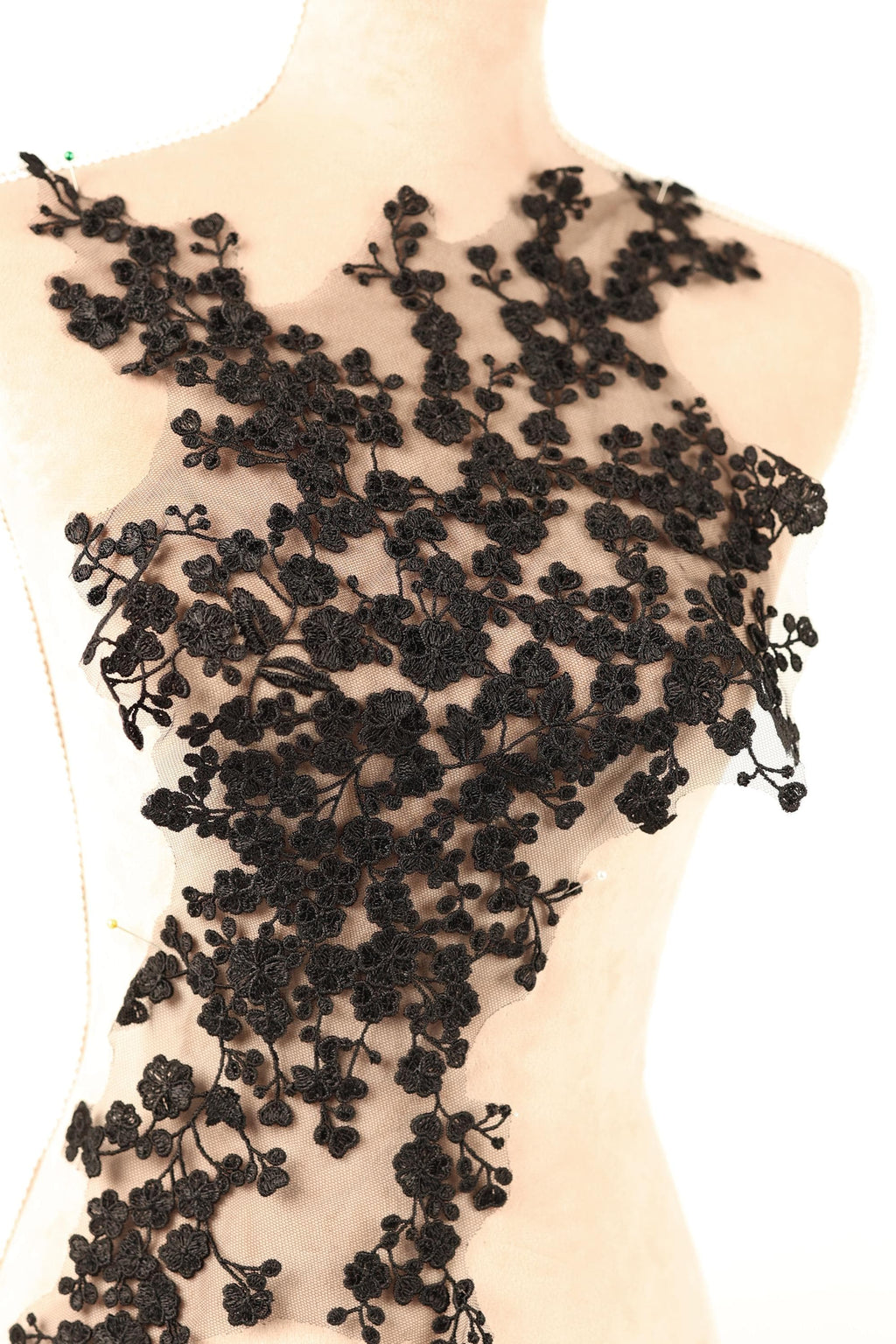 A mannequin wearing a dress with a black floral lace overlay.