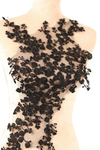 A mannequin wearing a dress with a black floral lace overlay.