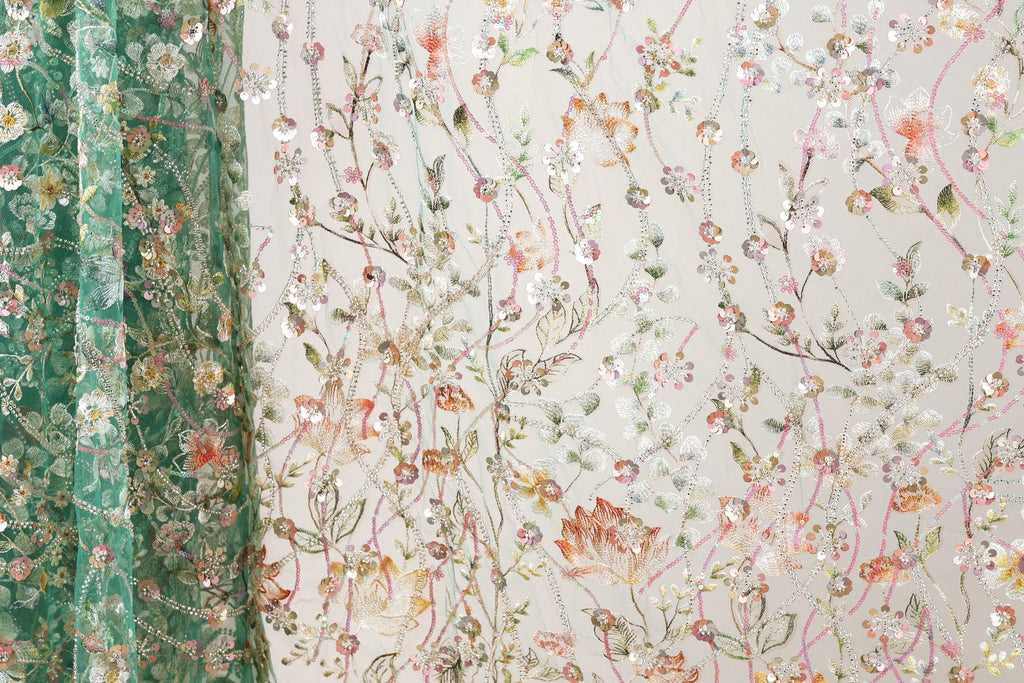 a close-up view of a fabric with a floral pattern, including various shades of green, pink, and white flowers and leaves. The fabric appears to be made of a sheer material, giving it a delicate and airy appearance. The pattern is intricate and detailed, showcasing the craftsmanship involved in creating the fabric.