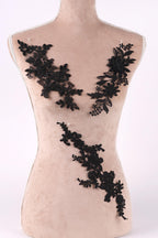 A mannequin torso with black lace appliques on it, including floral and leaf designs.