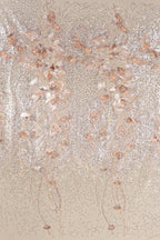 a close-up view of a beige fabric adorned with delicate, shimmering gold and white floral and leaf designs. The intricate patterns and textures create a visually striking and elegant appearance.