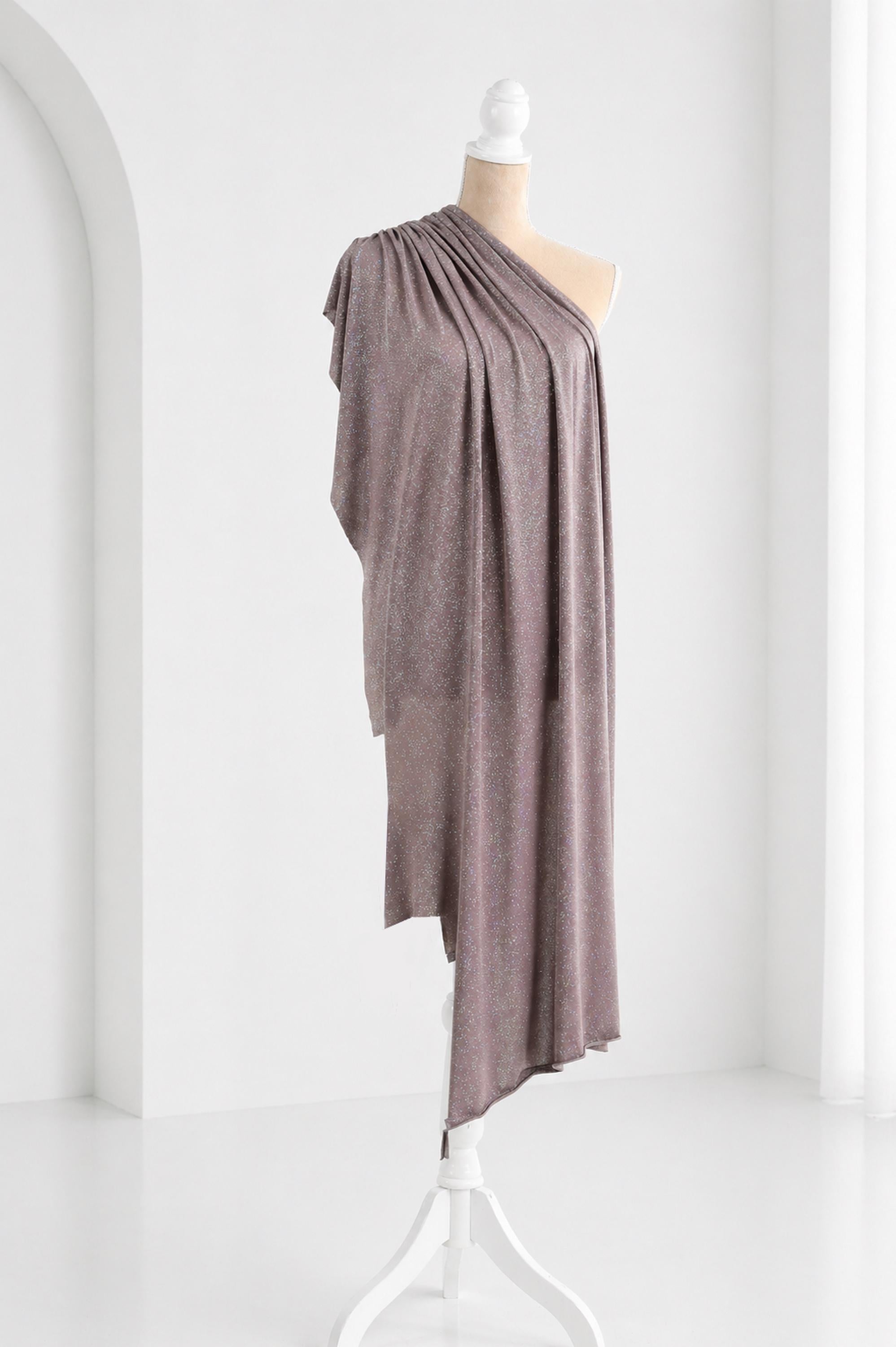 A mannequin wearing a one-shoulder gray dress with a draped, flowing design.