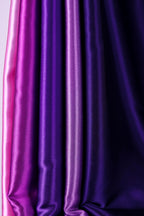 a close-up view of a collection of fabric swatches in various shades of purple and pink.