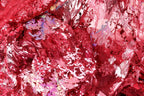 The image is a close-up of a fabric with a red and pink color scheme, featuring a variety of textures and patterns, including sequins and lace-like elements.