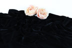 Two pink roses resting on a crumpled black fabric.
