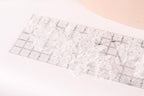 a close-up view of a clear ruler with a lace pattern on it, placed on a white surface.