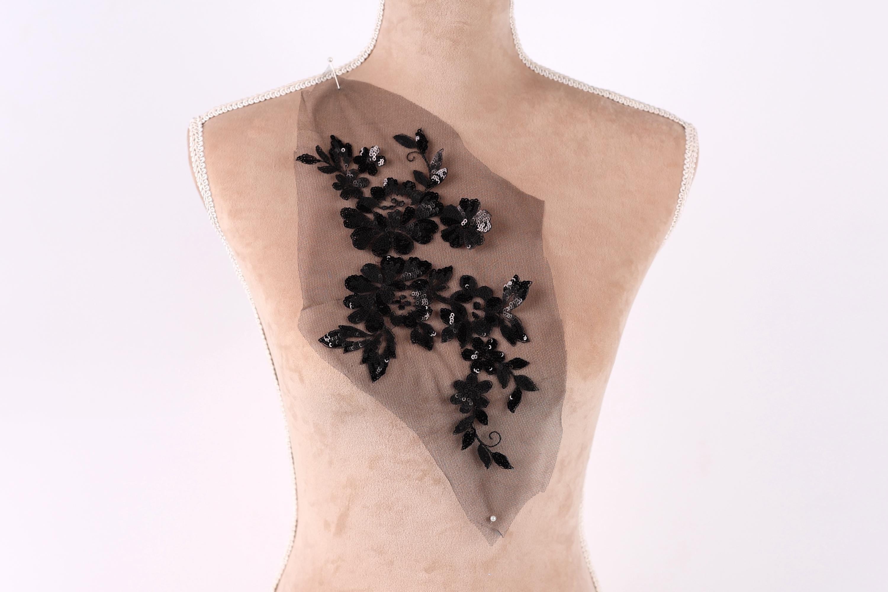 a mannequin torso with a decorative black floral embroidery on the back.