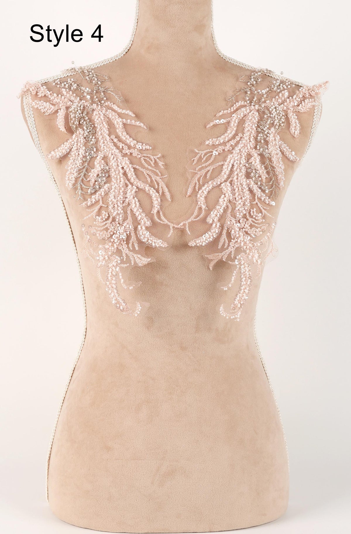 A mannequin with a beige body and delicate, intricate lace or beaded embellishments on the shoulders and back.