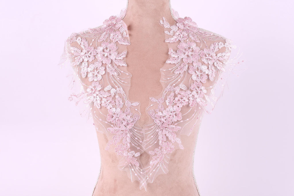 A mannequin wearing a delicate, lace-like collar with pink flowers.
