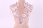 A mannequin wearing a delicate, lace-like collar with pink flowers.
