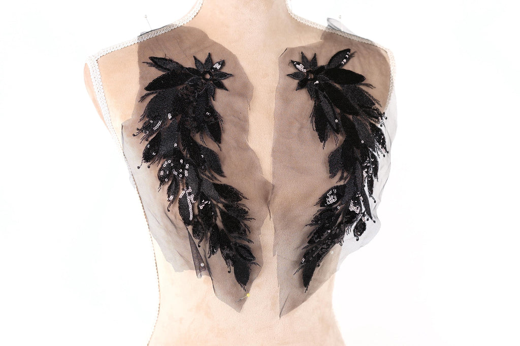 a mannequin torso with two large, black, feather-like embellishments on the back.
