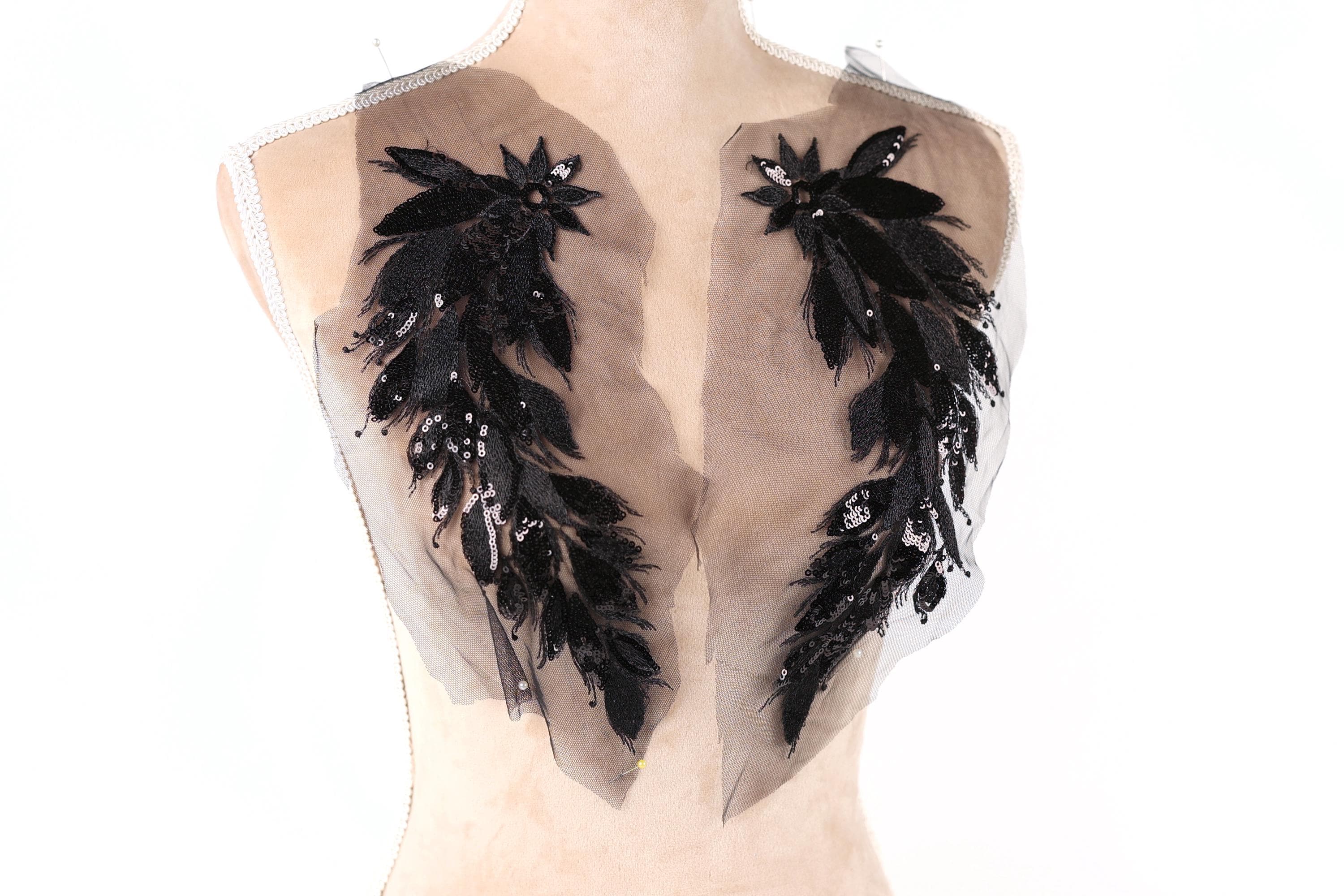a mannequin torso with two large, black, feather-like embellishments on the back.