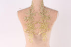 a mannequin torso with intricate gold embroidered floral designs on the back.