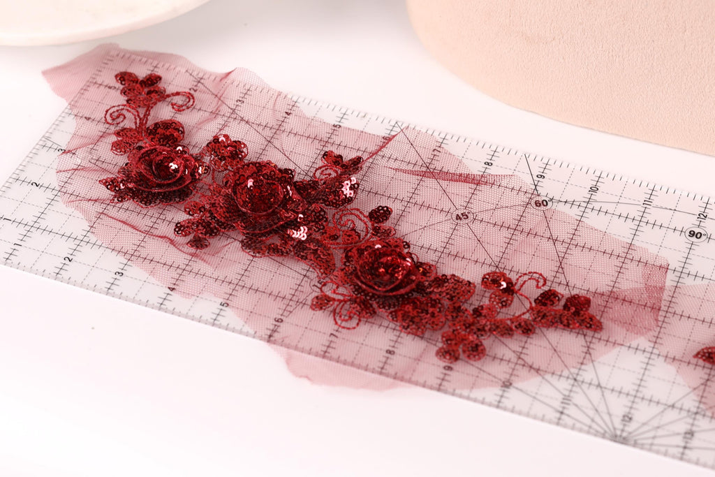 a close-up view of a transparent ruler with red sequin flowers placed on it.