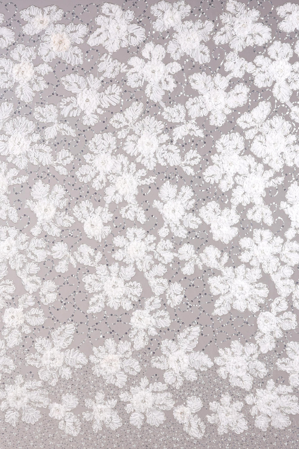 The image is a close-up of a fabric with a floral pattern, featuring numerous white flowers and leaves scattered across the surface.
