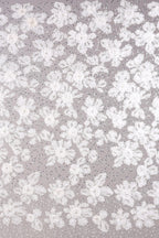The image is a close-up of a fabric with a floral pattern, featuring numerous white flowers and leaves scattered across the surface.