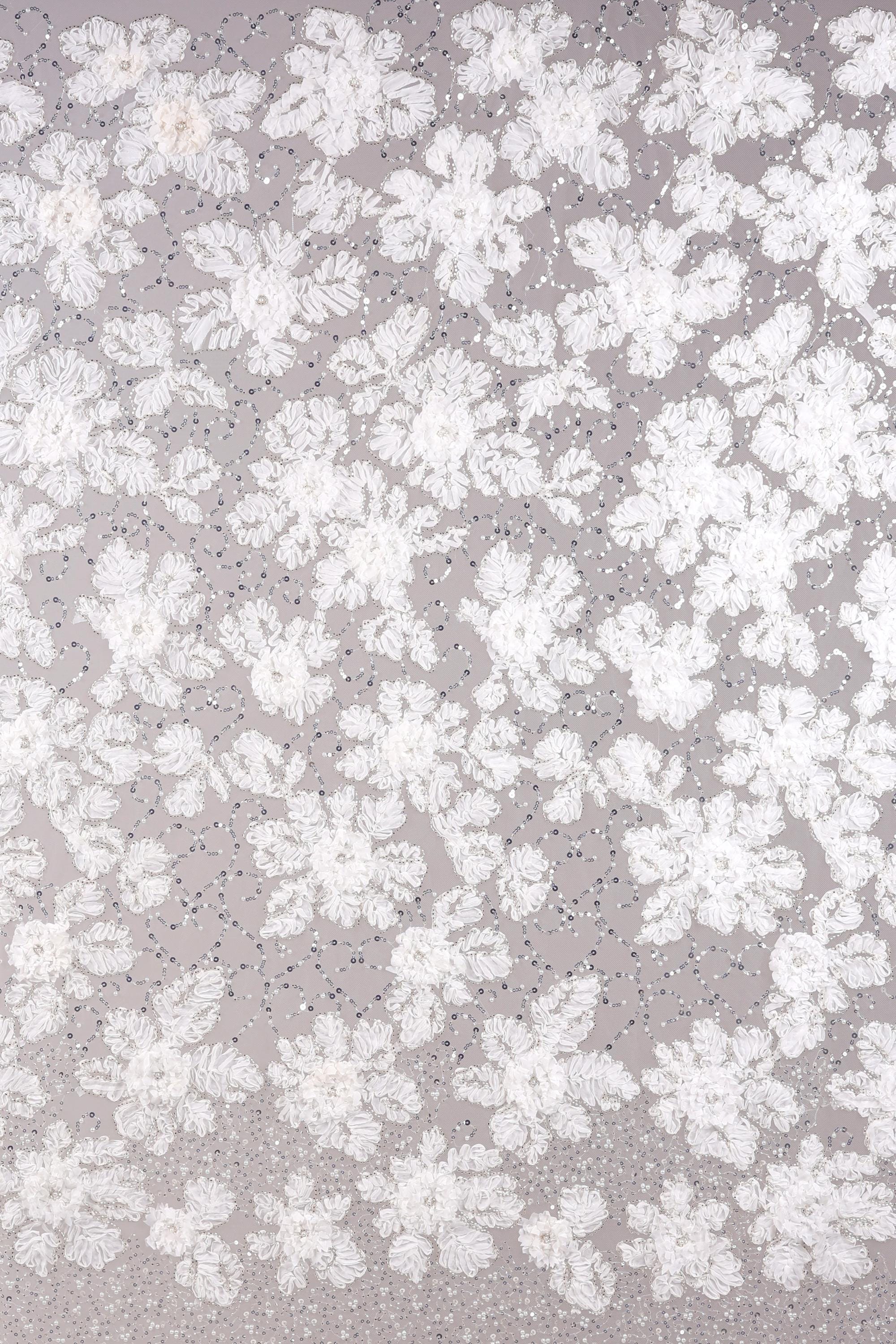 The image is a close-up of a fabric with a floral pattern, featuring numerous white flowers and leaves scattered across the surface.