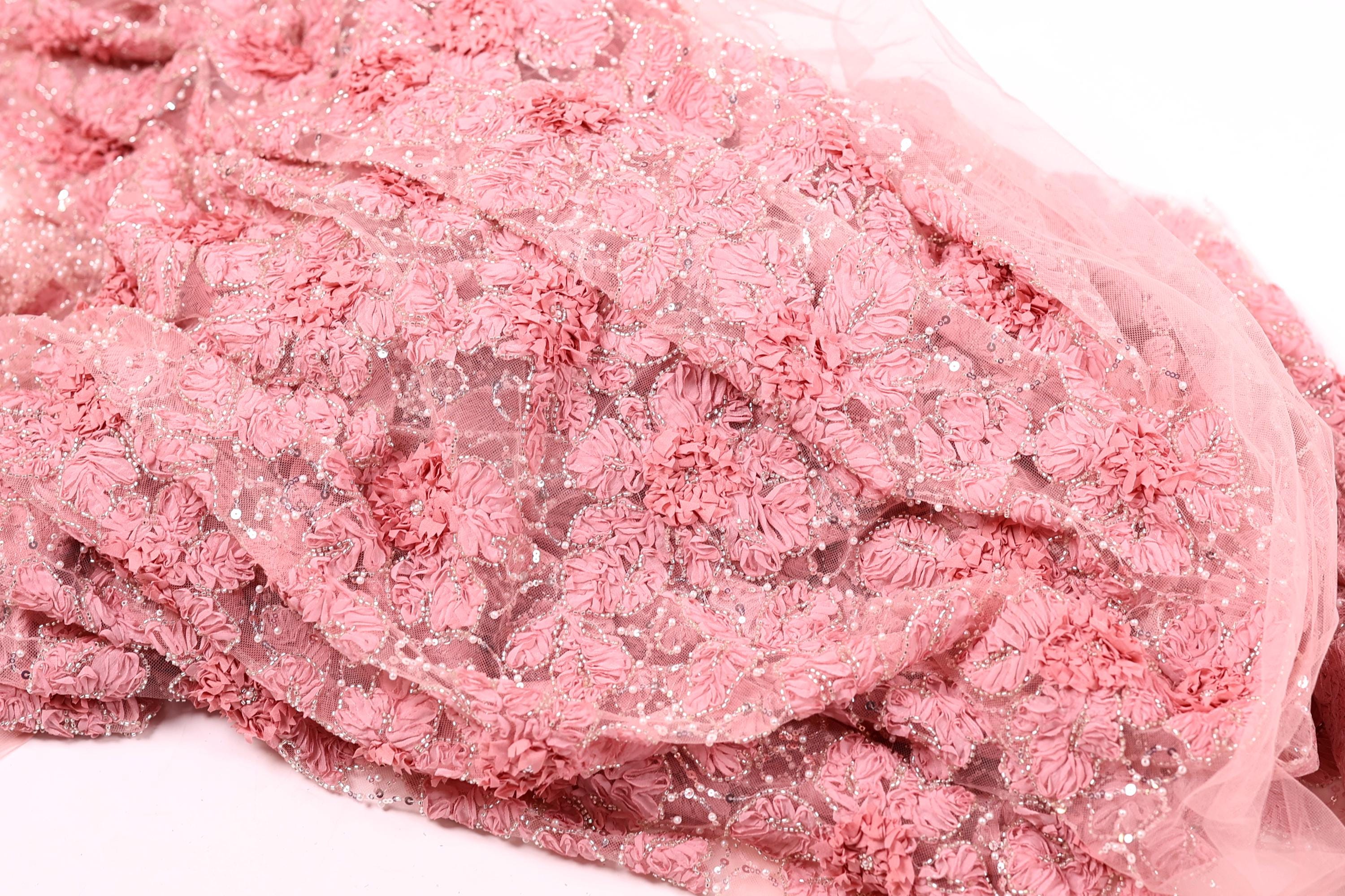 a close-up view of a fabric with a pink floral pattern, featuring numerous small pink flowers and leaves.