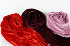 three different colored velvet fabric swatches, including red, burgundy, and pink velvet, arranged on a white background.