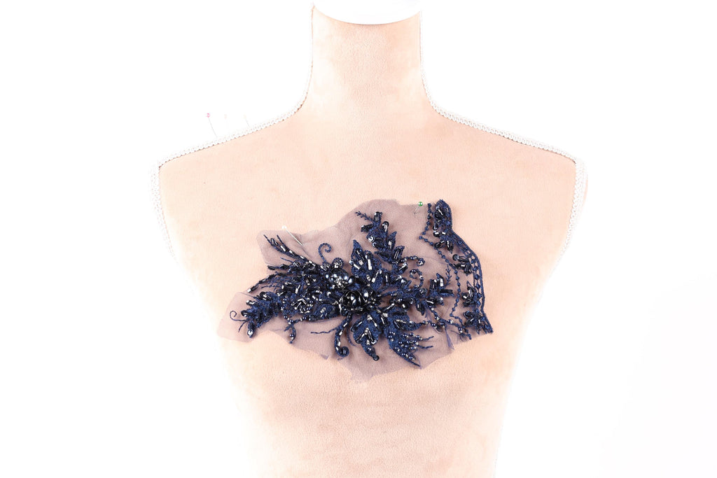A mannequin torso with a decorative blue lace or fabric piece sewn onto it.