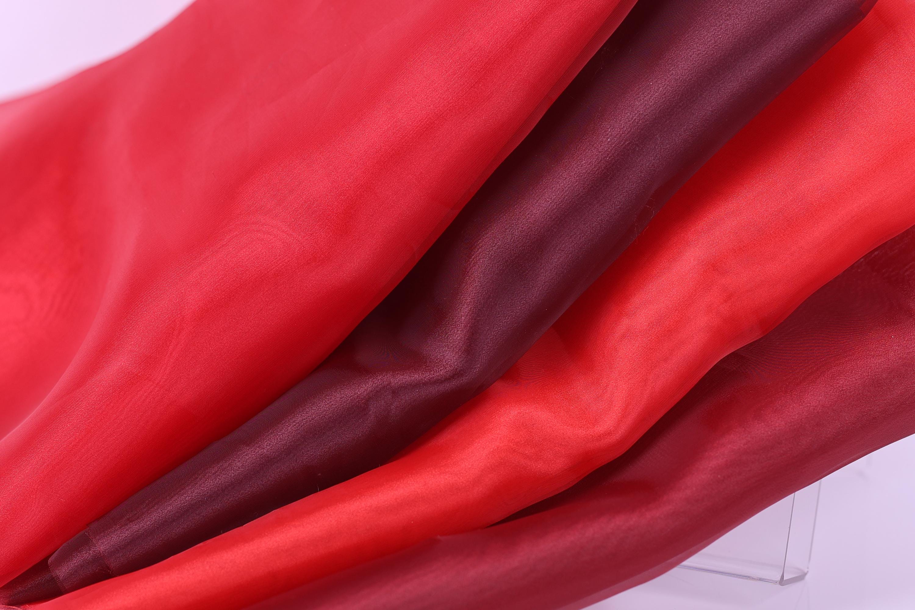 a close-up view of a fabric with a red and maroon color scheme, with the red fabric appearing more vibrant and the maroon fabric appearing more subdued.