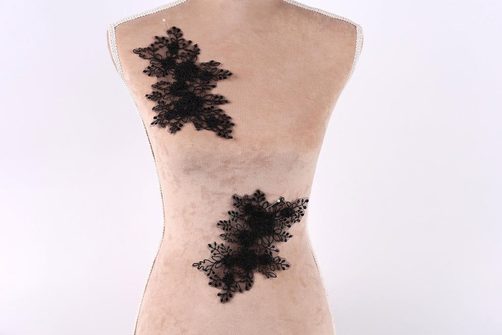 a mannequin torso with black lace appliques on it.