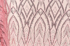 a close-up view of a fabric with a repeating pattern of pink and black sequin designs. The pattern consists of various shapes and lines, creating a visually striking and intricate design.