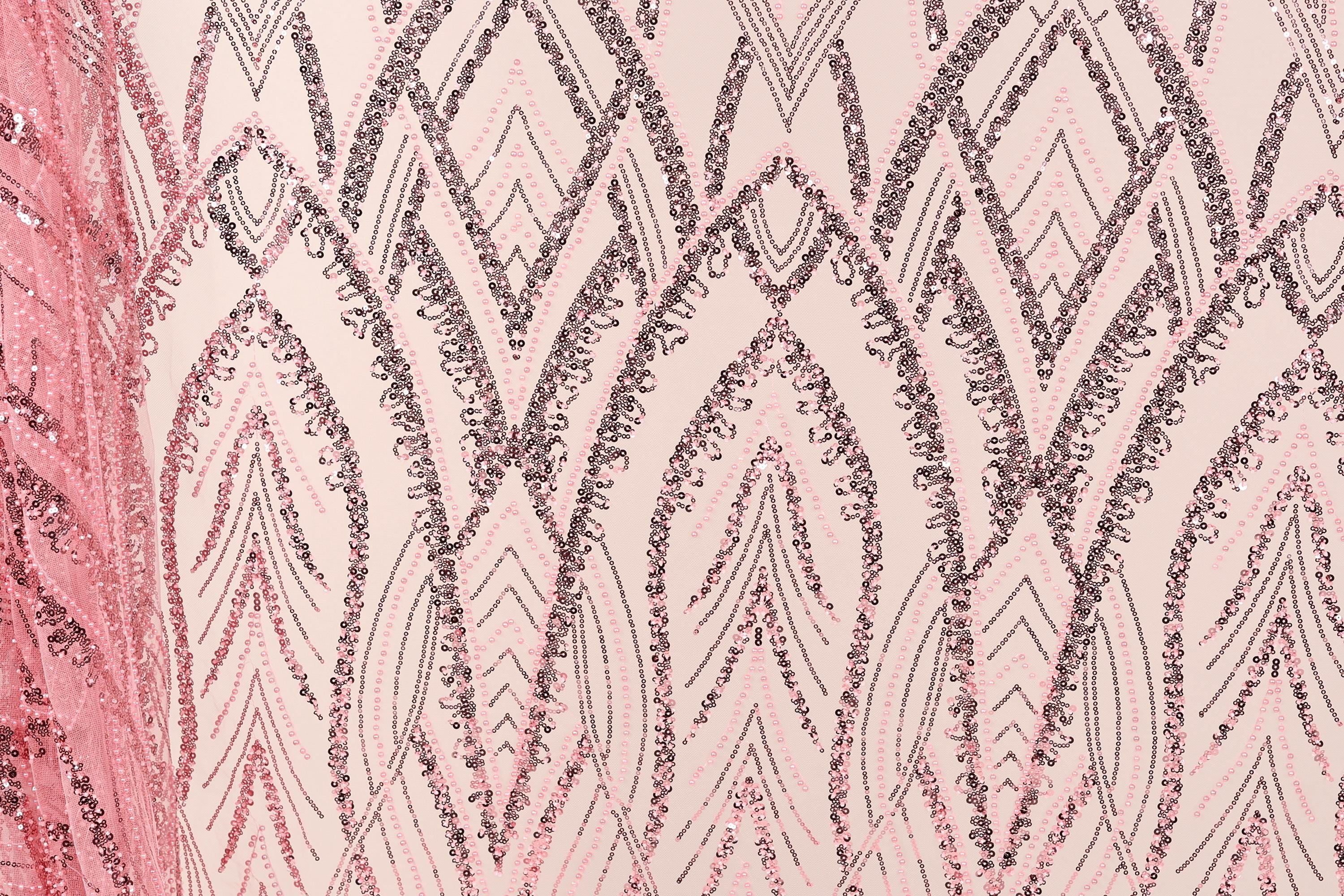 a close-up view of a fabric with a repeating pattern of pink and black sequin designs. The pattern consists of various shapes and lines, creating a visually striking and intricate design.